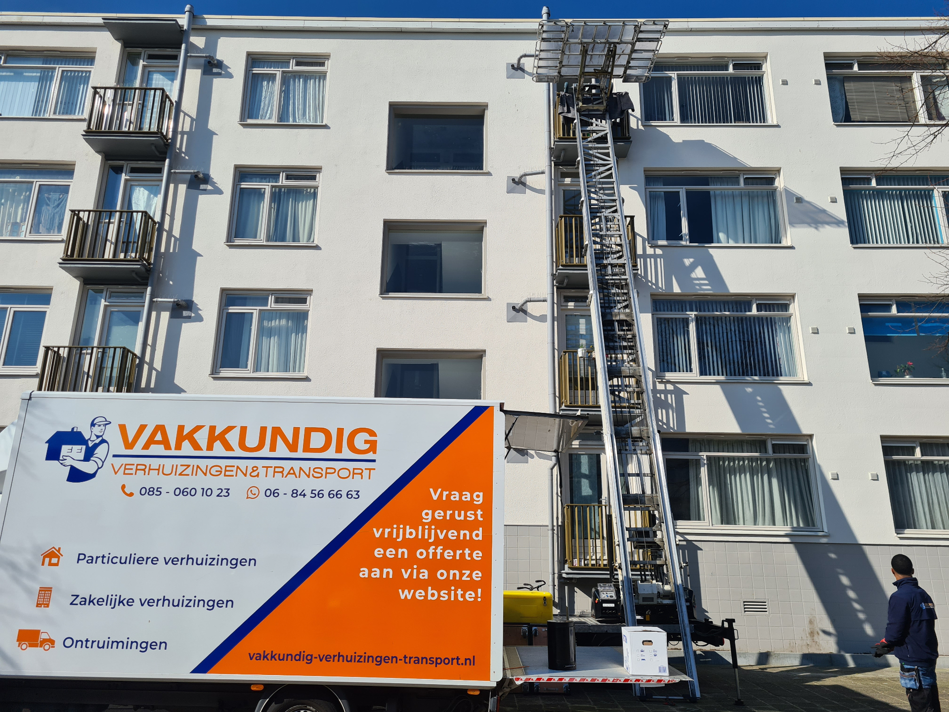 Verhuiswagen van Vakkundig met uitgeschoven verhuislift langs een appartementencomplex